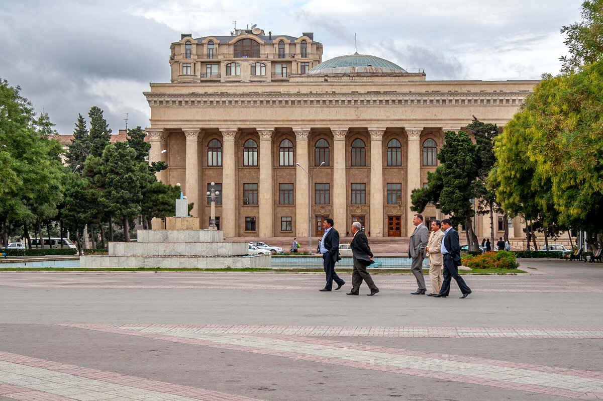 Suited men crossing a grand square